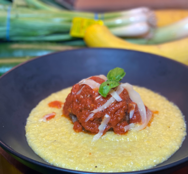 Giant meatball with tomato sauce in pool of soft polenta